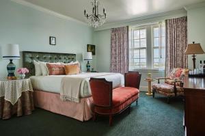 a bedroom with a bed and a chair and a chandelier at Pontchartrain Hotel St. Charles Avenue in New Orleans