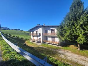 a white house with a fence in a field at Locazione turistica Cuore d'Altopiano ad Asiago con ricarica per E-Bike in Asiago
