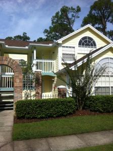 a white house with a porch and an archway at Villas at Laguna Bay in Kissimmee