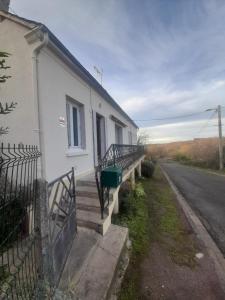 a white building with stairs next to a street at Séjour vert au calme in La Machine