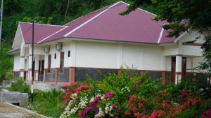 une maison au toit violet et quelques fleurs dans l'établissement Homestay, à Labuan Bajo 4 autres photos