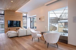 un soggiorno con mobili bianchi e una grande finestra di V Residence by H2 Life a Niseko