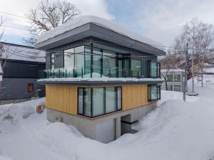 una casa ricoperta di neve con la neve intorno di V Residence by H2 Life a Niseko