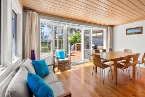 een woonkamer met een bank en een tafel bij Banksia Cottage - Pet Friendly Waterfront in Callala Bay