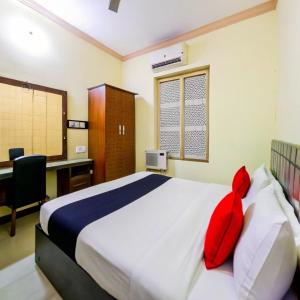 a bedroom with a bed with red pillows and a desk at PeaceWood in kolkata