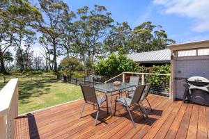 een houten terras met een tafel en stoelen erop bij Banksia Cottage - Pet Friendly Waterfront in Callala Bay