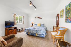 een slaapkamer met een bed, een tv en een bank bij Banksia Cottage - Pet Friendly Waterfront in Callala Bay