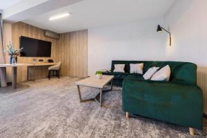 a living room with a green couch and a table at Hotel Pod Jedlami in Wisła