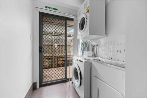 a white kitchen with a washer and dryer at Charming 3-Bed Home Near Sunshine Coast in Caloundra West