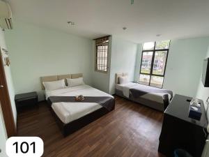 a room with two beds and a desk and two windows at Ezzyhome Taman Molek in Johor Bahru