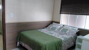 - une petite chambre avec un lit et une fenêtre dans l'établissement Kitnet no Centro de Bombinhas, à Bombinhas