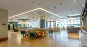 eine Lobby mit Tischen, Stühlen und einem Kronleuchter in der Unterkunft Magnotel Business Yangzhou China Grand Canal Museum Wanda Plaza in Yangzhou