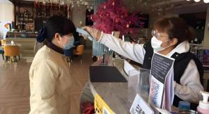 zwei Frauen mit Gesichtsmasken, die an einem Tresen stehen in der Unterkunft Magnotel Business Yangzhou China Grand Canal Museum Wanda Plaza in Yangzhou