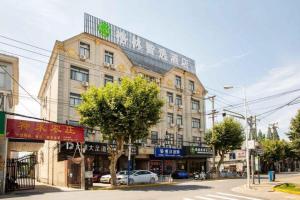 een groot gebouw in een straat met auto's aan de voorkant bij GreenTree Inn Shanghai Luojing Express Hotel in Luojing