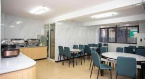 een eetkamer met tafels en stoelen en een keuken bij GreenTree Inn Shanghai Luojing Express Hotel in Luojing