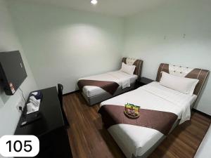 a hotel room with two beds and a table at Ezzyhome Taman Molek in Johor Bahru