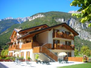 un bâtiment avec des tables et des chaises en face d'une montagne dans l'établissement Garnì Lago Alpino, à Molveno