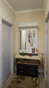 een badkamer met een wastafel, een spiegel en een deur bij Khatuna Home in Tskaltubo