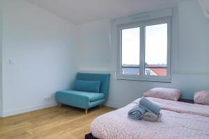 1 dormitorio con 2 camas y silla azul en Le Magelan, en Vaires-sur-Marne
