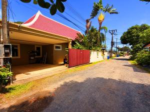 una casa con una puerta roja en una calle en Spacious Authentic Thai-style Pool Villa Rawai, en Ban Saiyuan (1)