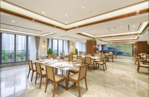 een eetkamer met tafels, stoelen en ramen bij Nanjing Rsun Hotel in Taishan