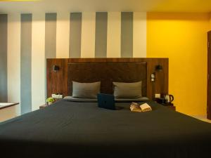 a bed with a laptop and a book on it at The Hosteller Gokarna in Gokarna