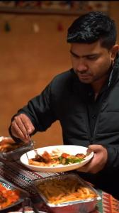 a man is holding a plate of food at Desert Wonders Camp in Ḩawīyah