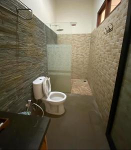 a bathroom with a toilet and a brick wall at Mojosurf Red Island in Pulau Lutung