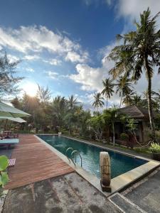 a pool with a wooden deck next to a resort at Mojosurf Red Island in Pulau Lutung