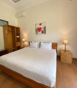 a bedroom with a large white bed and two lamps at Mojosurf Red Island in Pulau Lutung