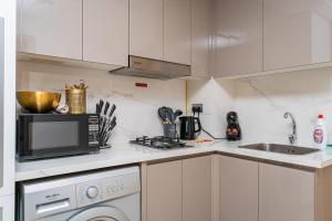 eine weiße Küche mit Mikrowelle und Geschirrspüler in der Unterkunft Premium Nest - Serene Homes in Sabkhah