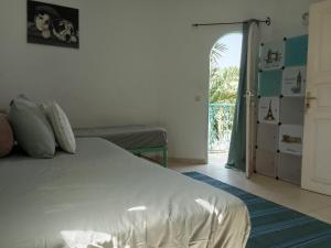 a bedroom with a white bed and an open door at Charming duplex - Villa Bleue Majorelle, Saly in Saly Portudal