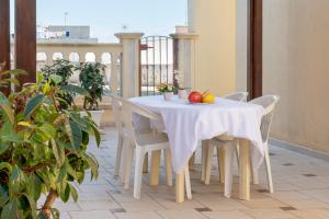 una mesa blanca con sillas y fruta en el balcón en Olimpo, en Giurdignano