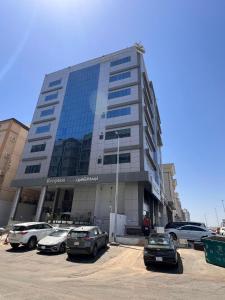a large building with cars parked in a parking lot at Alshaheen Suites in Jeddah