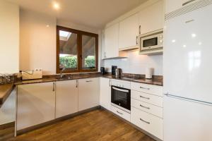 eine Küche mit weißen Schränken und einem Fenster in der Unterkunft Casa Rural El Castro in La Revilla