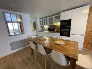 eine Küche und ein Esszimmer mit einem Holztisch und Stühlen in der Unterkunft Chaleureux appartement Altitude 1500 in Le Lioran