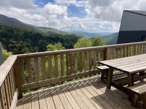 eine Holzterrasse mit einem Picknicktisch und Aussicht in der Unterkunft Chaleureux appartement Altitude 1500 in Le Lioran