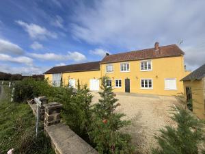 a yellow house with a driveway in front of it at La Maison des Vergers in Teloché