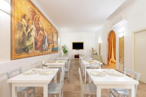 Un comedor con mesas blancas y un cuadro en la pared. en Olimpo, en Giurdignano