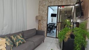 een woonkamer met een bank en wat planten bij suítes Pitanga in Maceió
