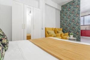ein Schlafzimmer mit einem Bett und einem gelben Stuhl in der Unterkunft Estudio Céntrico Santa Cruz in Santa Cruz de Tenerife