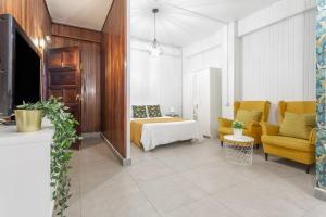 ein Schlafzimmer mit einem Bett und ein Wohnzimmer mit gelben Stühlen in der Unterkunft Estudio Céntrico Santa Cruz in Santa Cruz de Tenerife