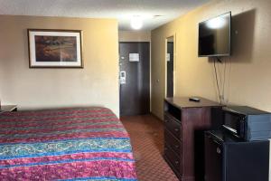 a hotel room with a bed and a flat screen tv at Broadway INN & SUITES OKC in Oklahoma City