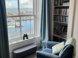 een woonkamer met een raam met uitzicht op een haven bij Westcliff in Penzance