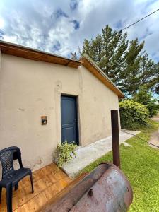 a house with a black chair and a blue door at Vientos del Lago - Tu refugio en la Patagonia in Los Antiguos