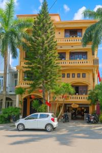 フエにあるPerfume Homestay Huếのヤシの木の建物前に停めた車