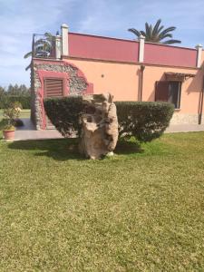 a house with a tree stump in the yard at Le sei palme B&B in Terralba