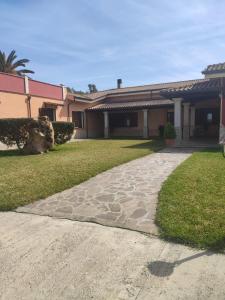 a house with a stone walkway in front of a yard at Le sei palme B&B in Terralba