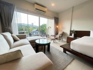 a hotel room with a couch and a bed and a table at The Langstan Suites in Nai Harn Beach
