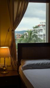 a bedroom with a window with a bed and a lamp at Seneh Homes in Guwahati